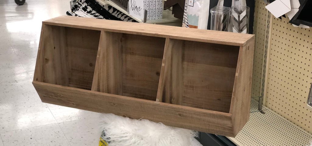 three wood cubby shelves sitting on top of white fur stool in store aisle