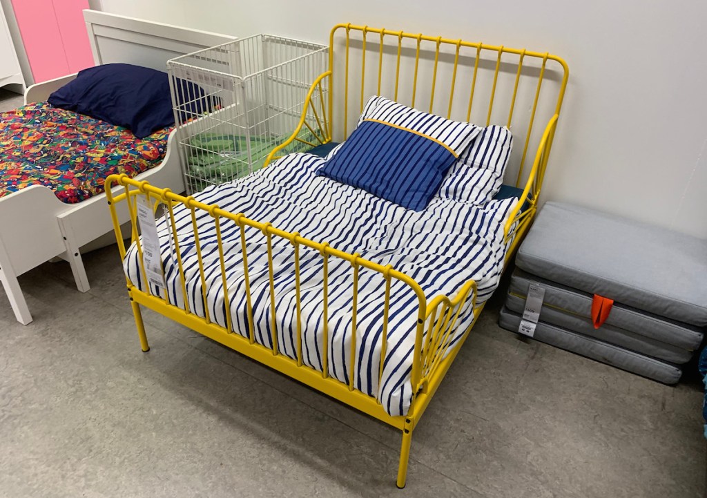 yellow iron bed next to white bed with blue pillows and blankets