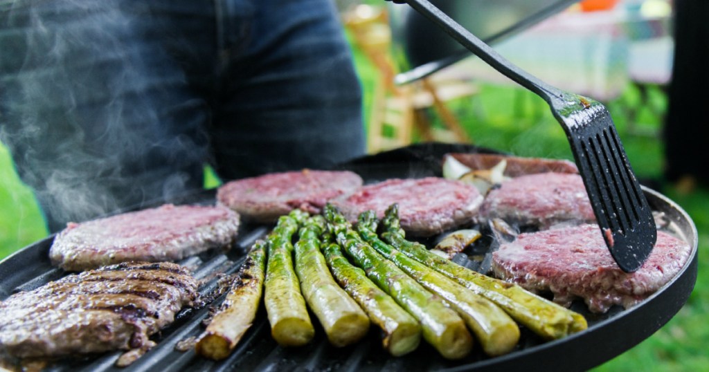 person grilling meats and veggies on grill