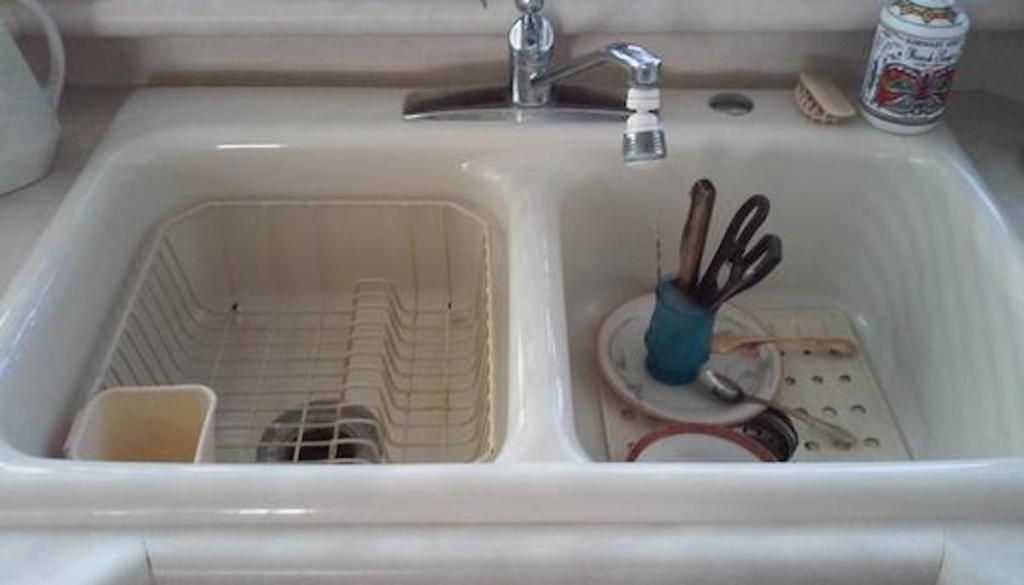 dirty white sink with nasty dishes silverware and cup with old sink faucet