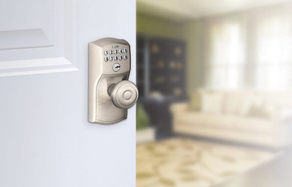 silver door knob and keypad lock on white door with living room blurred in background