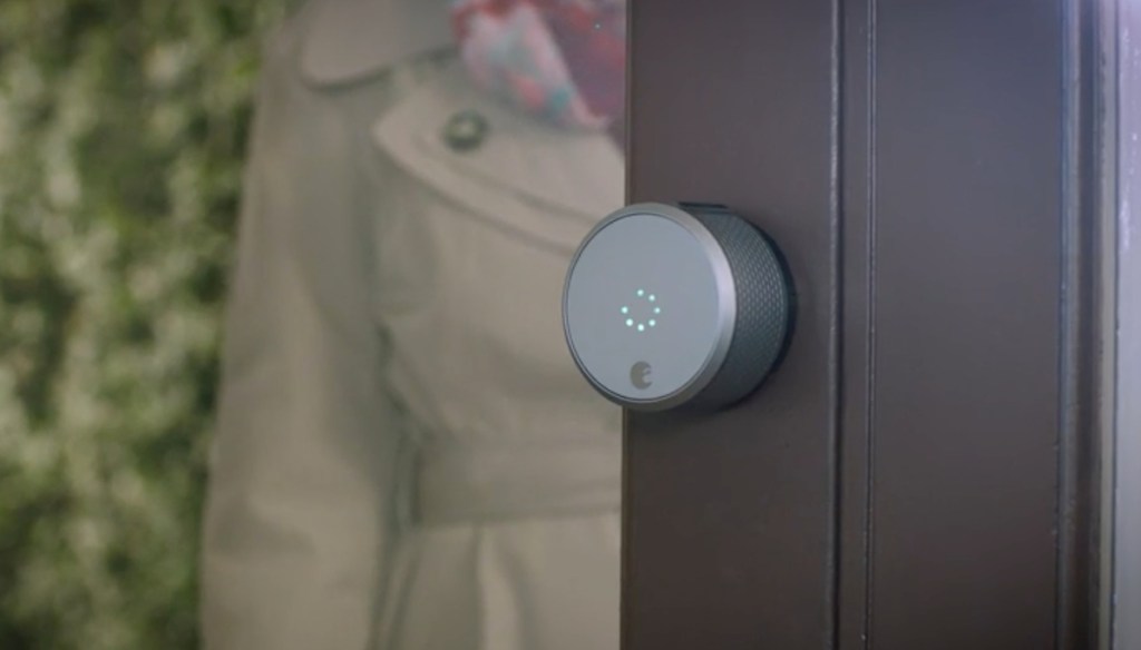 glass door with round device on edge of door with person in trench coat in the background