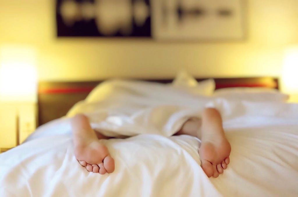 feet sticking out of white bed sheets 