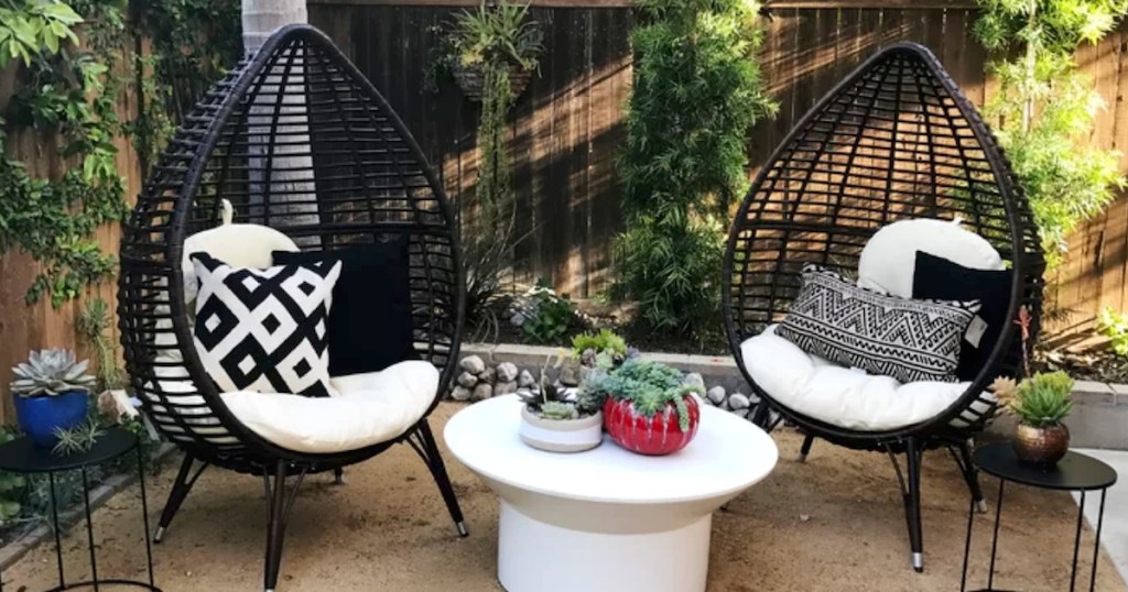 two black teardrop shaped chairs outside on a patio