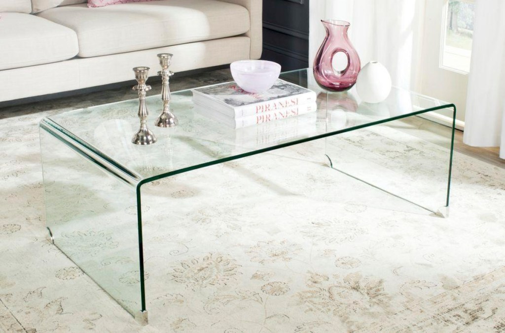 clear coffee table with silver candle sticks and pink vases and books