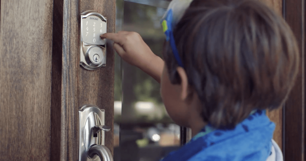 boy pushing digital lock keypad buttons on wood and glass front door