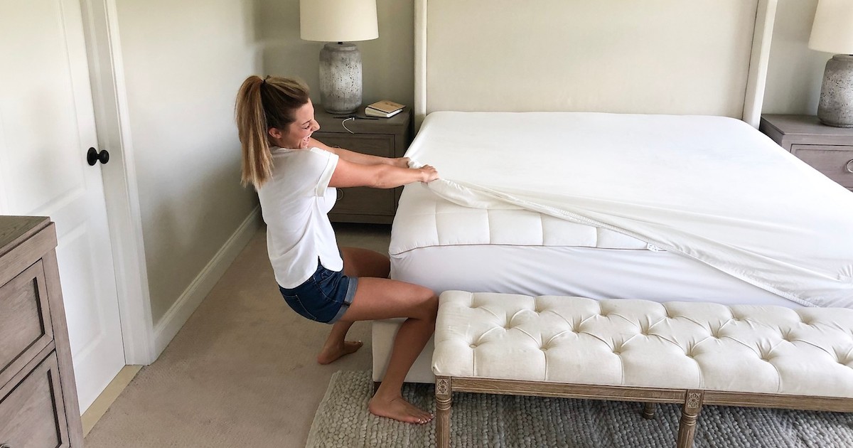 woman struggling to put on white fitted sheet on mattress