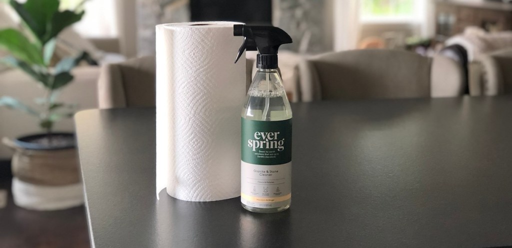 white roll of paper towels on black countertop next to bottle of gray everspring granite and stone cleaner