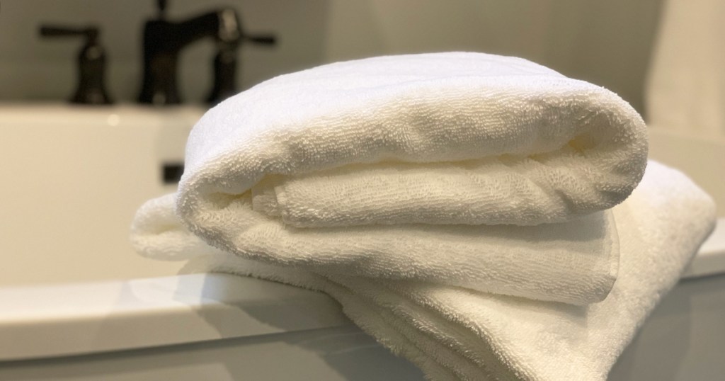 a stack of towels on the side of a bath tub