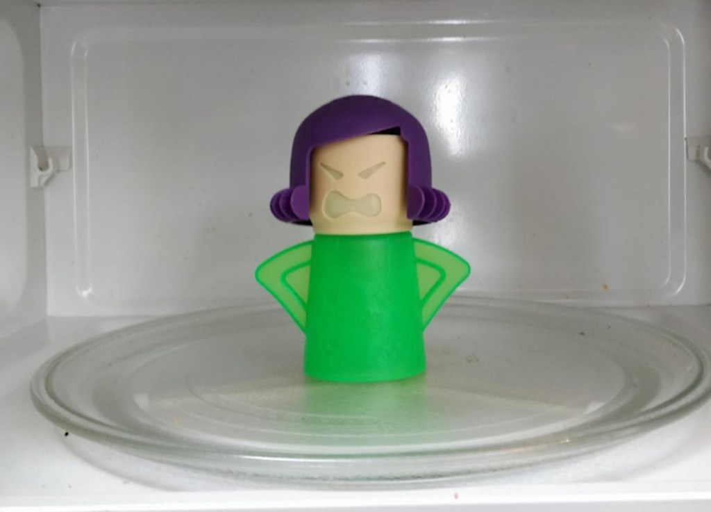 inside of white microwave with green and purple plastic lady