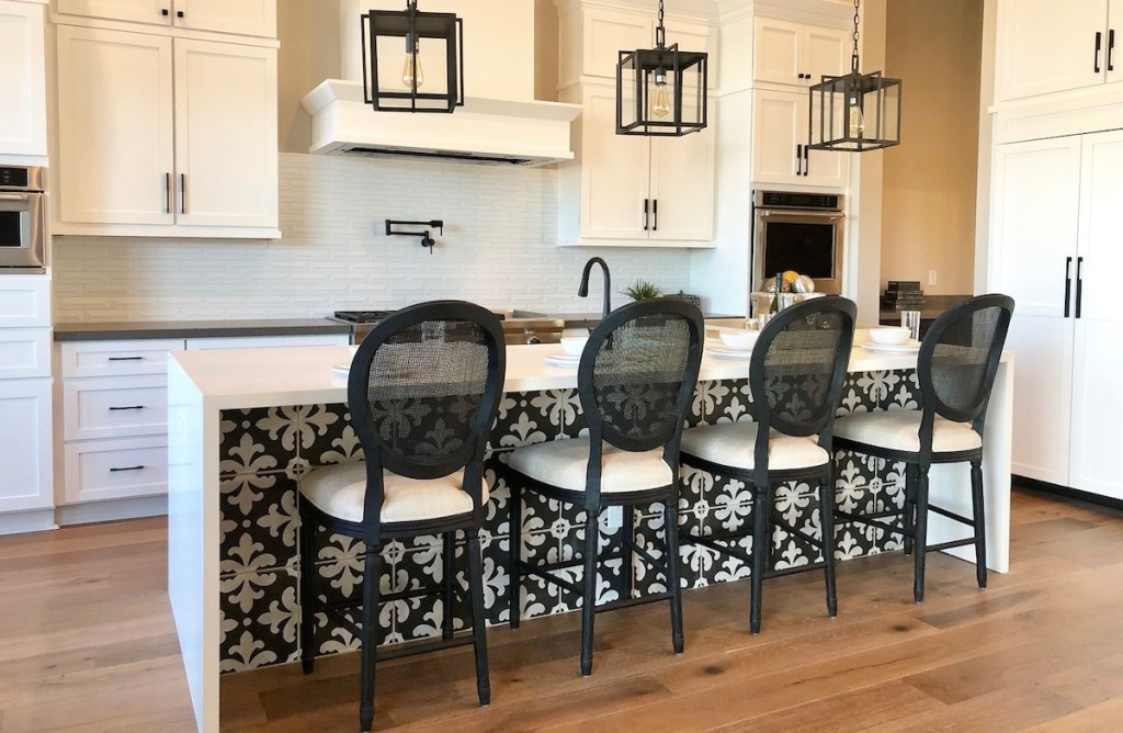 white kitchen cabinets with bold black round rattan barstools 