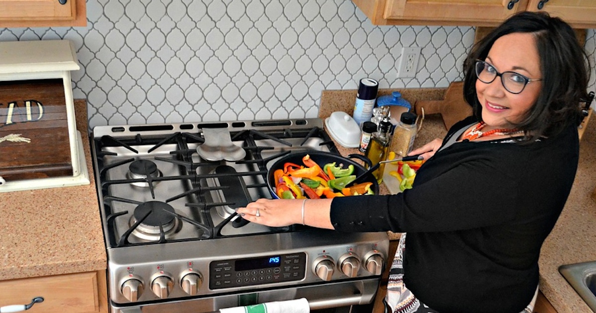 woman cooking colorful vegetables on gas stainless steel cooktop range