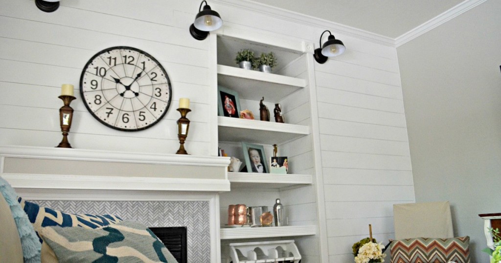 white shiplap wall with fireplace three black farmhouse barn lights and bookshelves