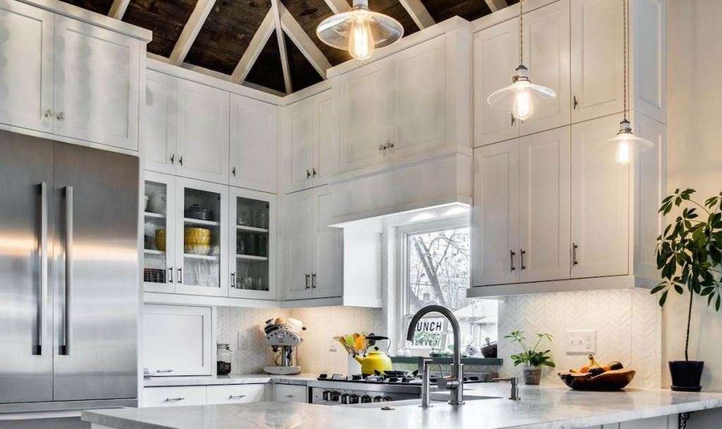white kitchen cabinets with high ceilings white beans and wood plants on surface