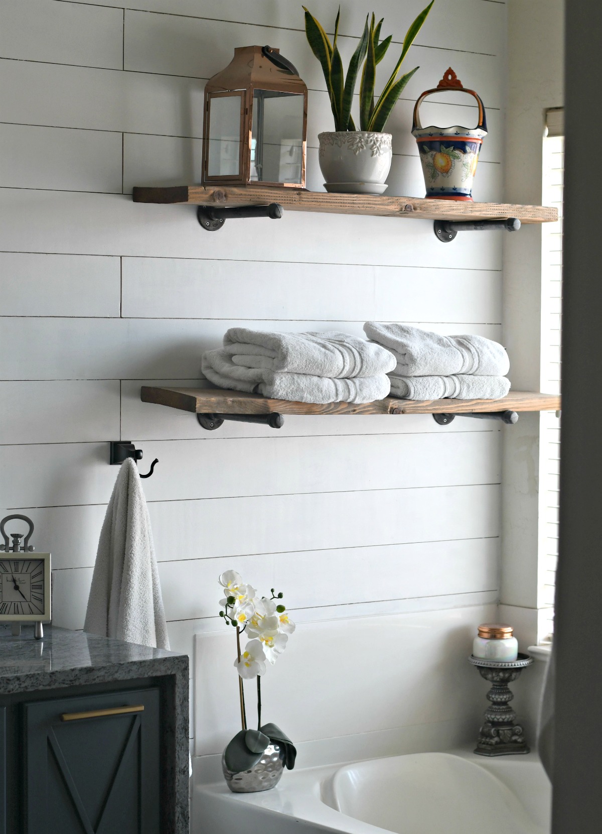 wood and pipe shelving above bath tub for towel storage