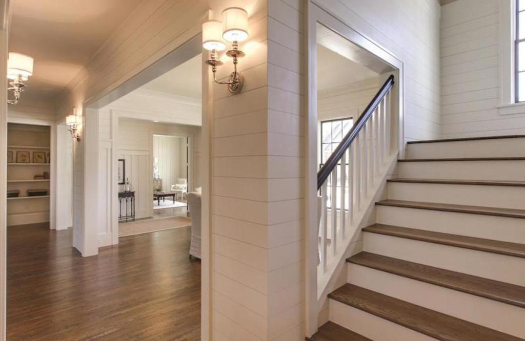 foyer in house with white shiplap walls and open floor plans with white walls and large wood staircase