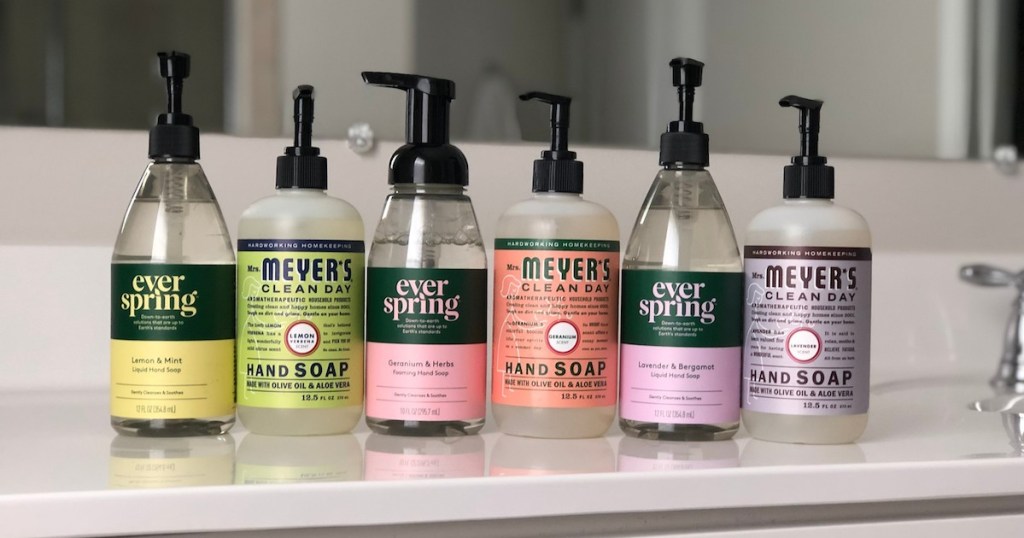 yellow green pink orange and two purple hand soaps lined up on white countertop