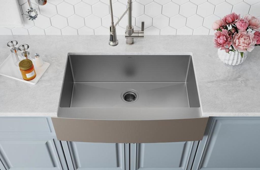 stainless steel sink with white countertops blue cabinets and white backsplash