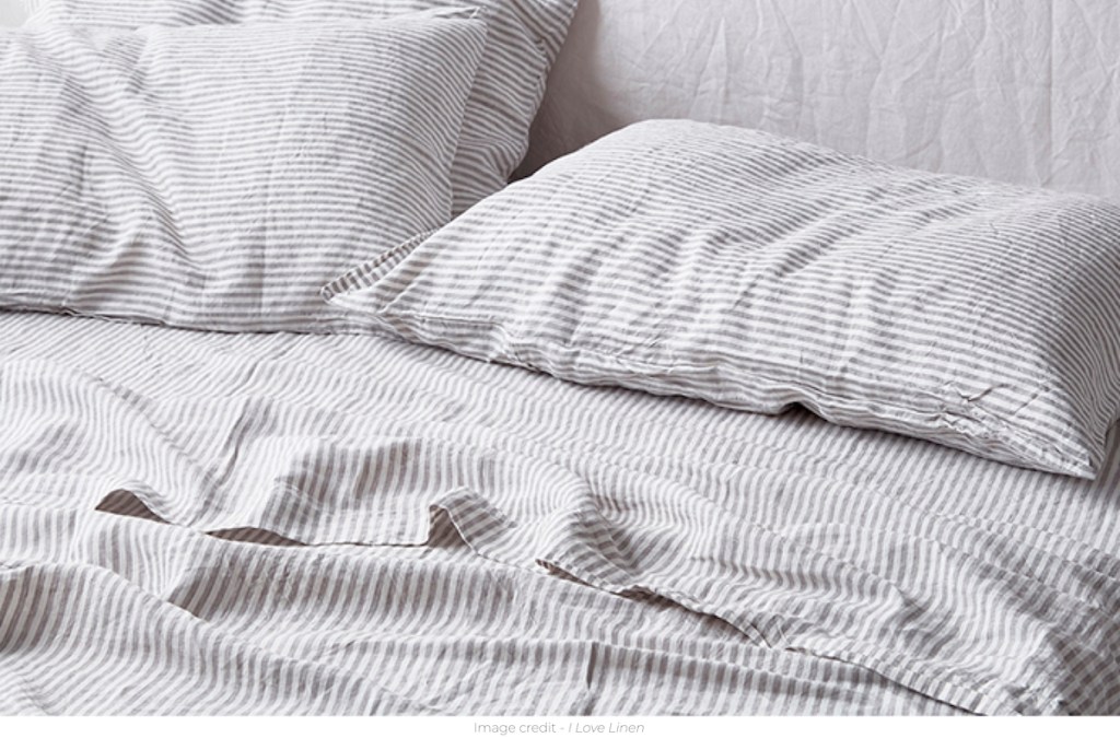white and gray ticking stripe sheets on bed with pillows 
