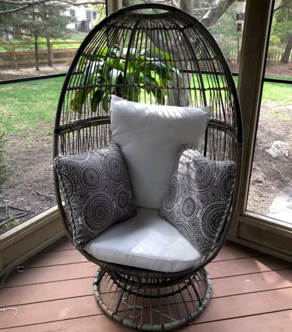 tall black egg chair with stand and white cushions decorative pillows