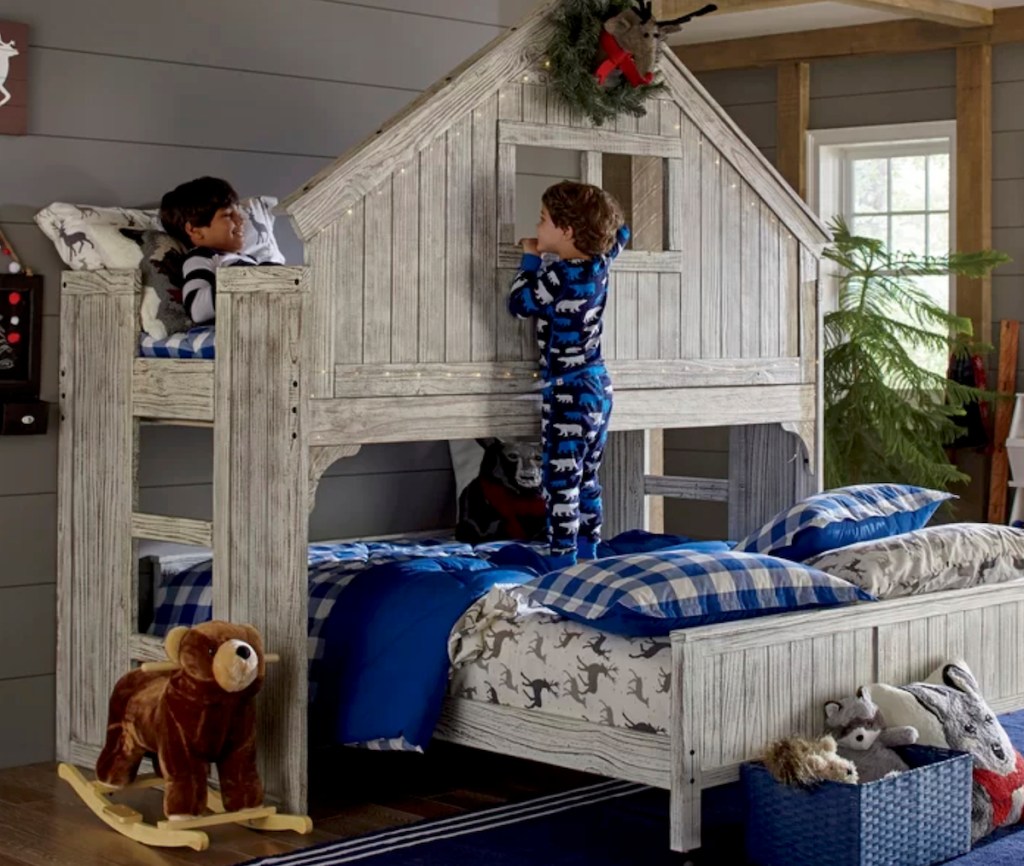 two boys playing on a twin over full wooden bunk bed