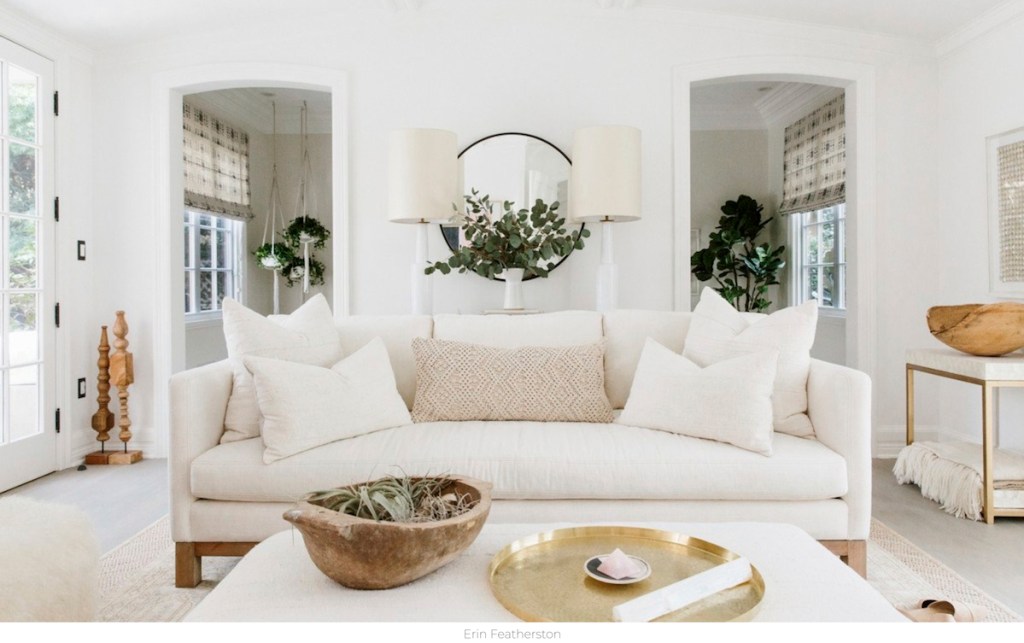 white living room with white walls beige couch soda with pillows and coffee table with decor