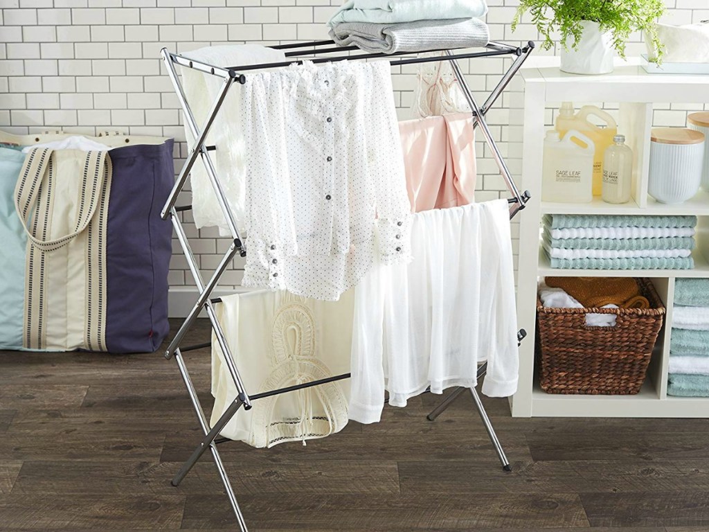 AmazonBasics Foldable Clothes Drying Laundry Rack with clothes hanging on it