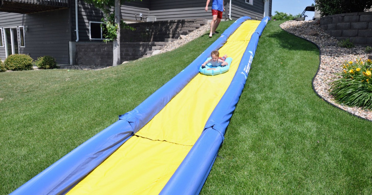 Boy on water sled sliding down super long yellow and blue water slide