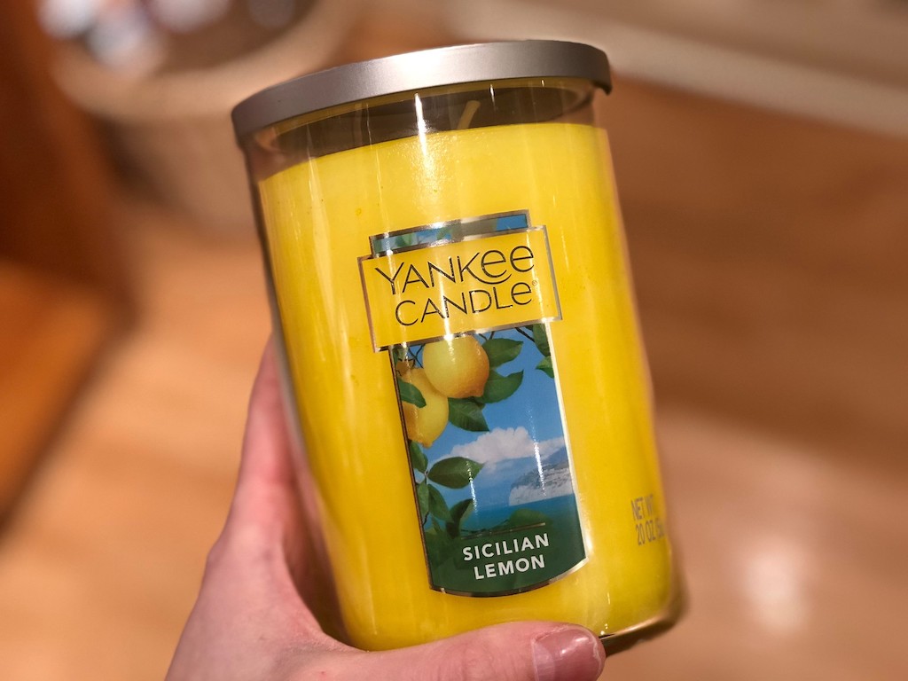 holding large yankee candle tumbler in sicilian lemon scent 