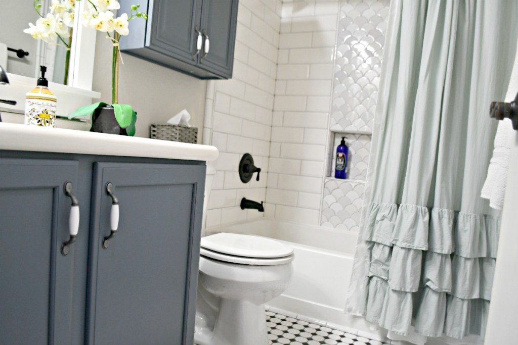 bathroom with blue cabinets and ruffle shower curtain 