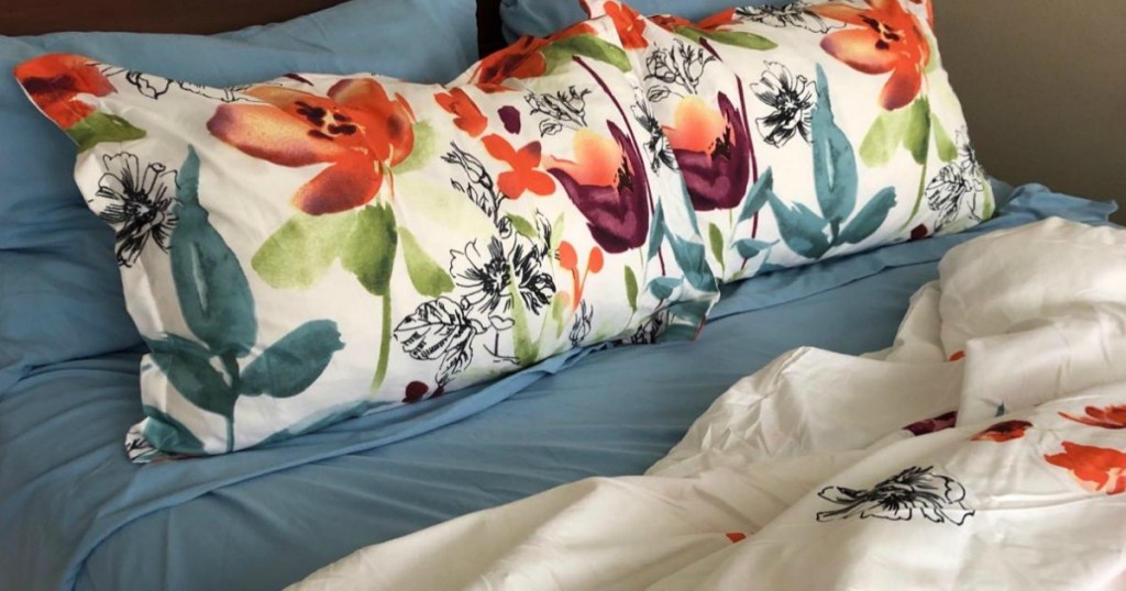 blue sheets and foral pillows on bed 