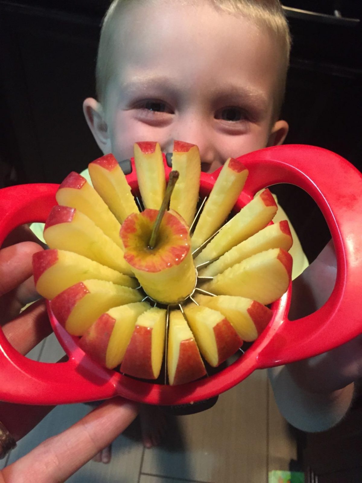 boy holding apple slice and corer 