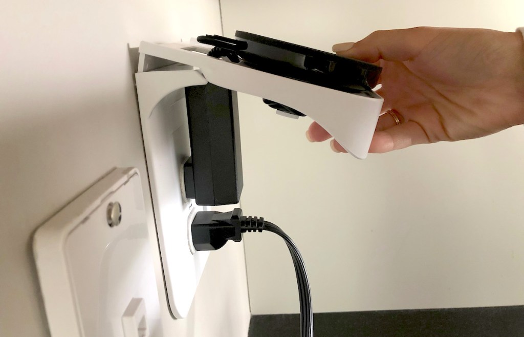 hand holding top of white outlet shelf with phone charger