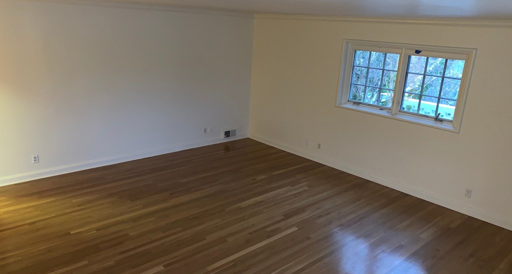 empty room with wood floors white walls and two small windows