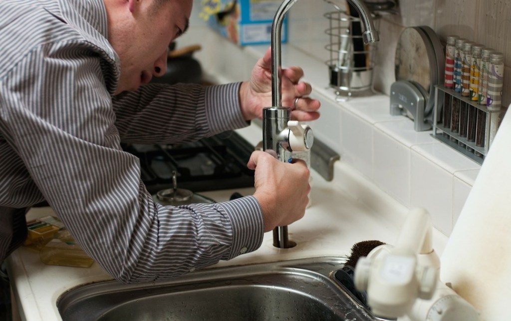 man fixing stainless steel sink faucet