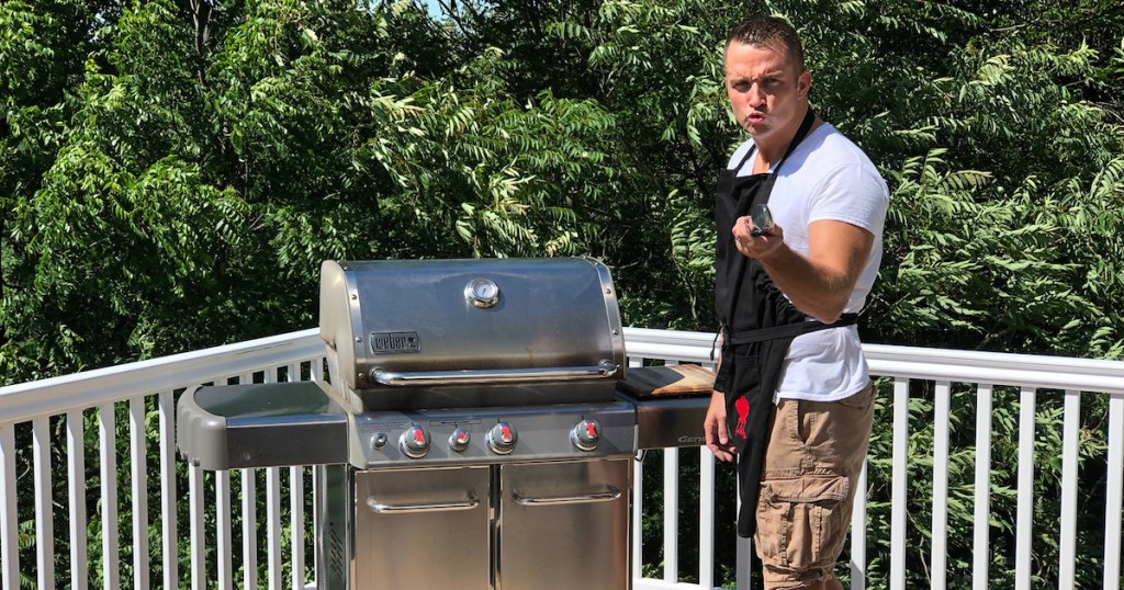 man standing next to stainless steel weber grill outside
