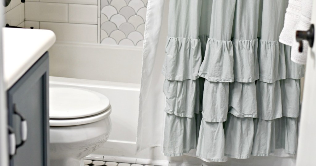 ruffle shower curtain with liner behind it in the bathroom 