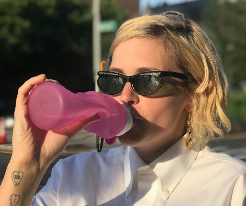 woman drinking out from pink silicone water bottle