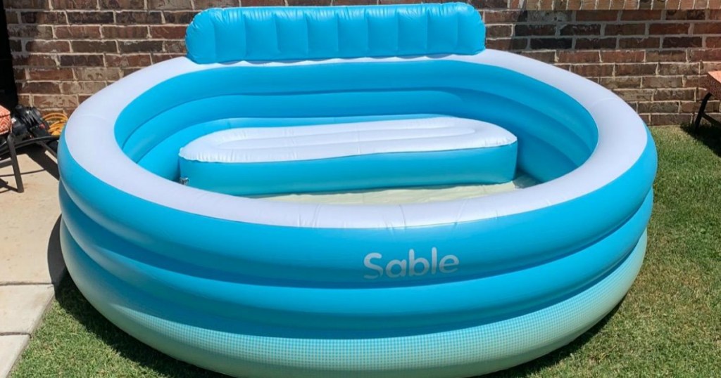 large inflatable pool with bench in backyard on grass