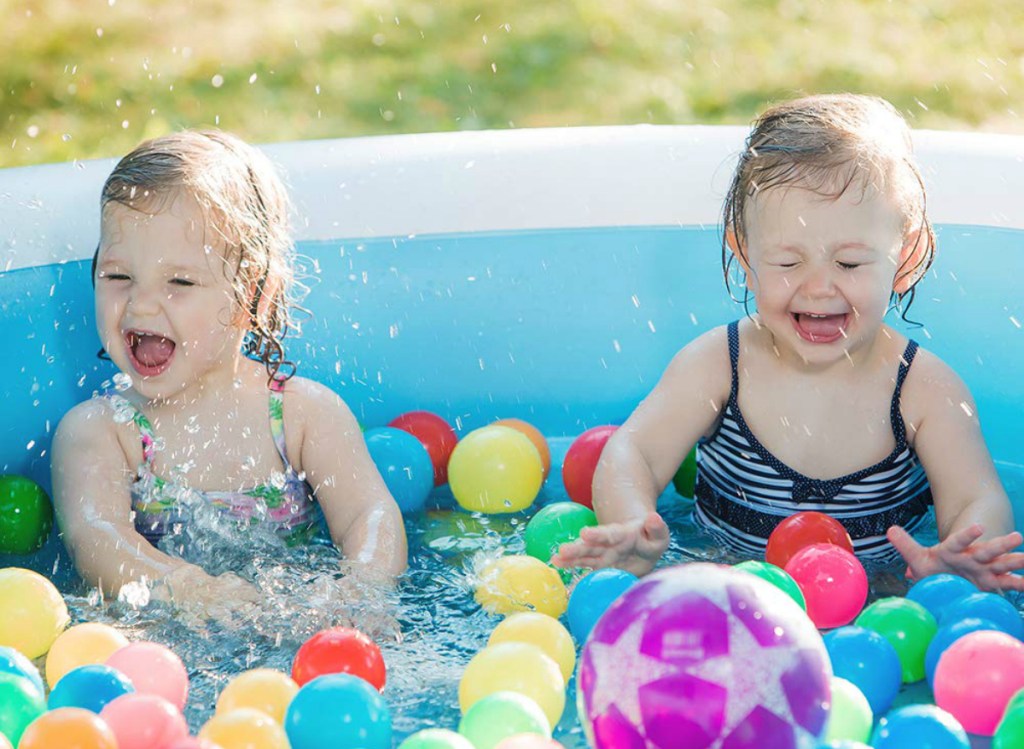 little girls having fun in inflatable pool with balls 