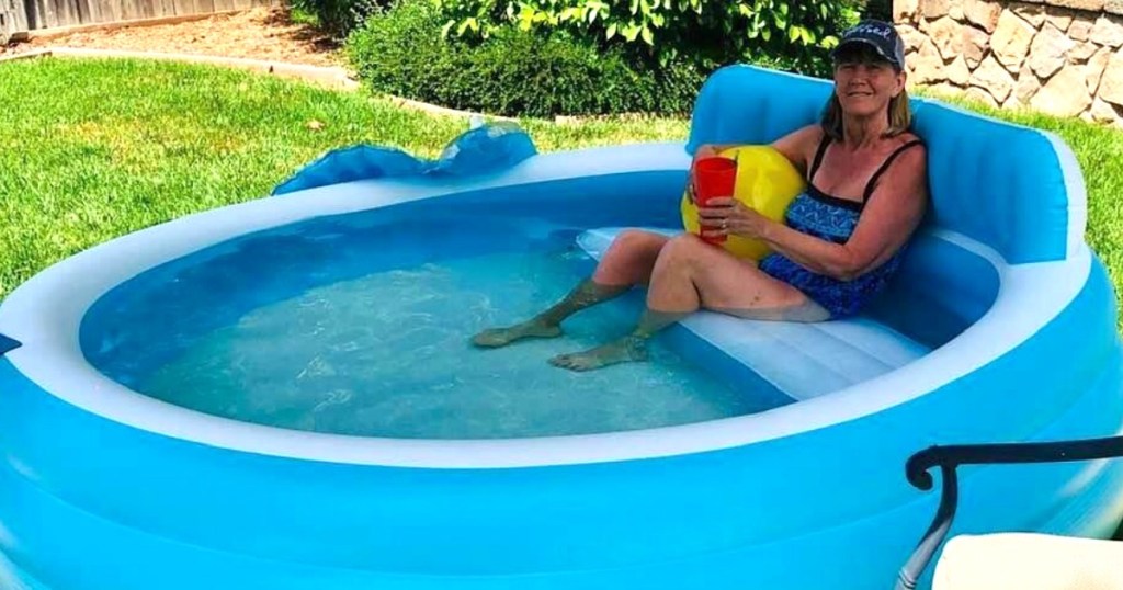 lady sitting in large inflatable pool with drink 