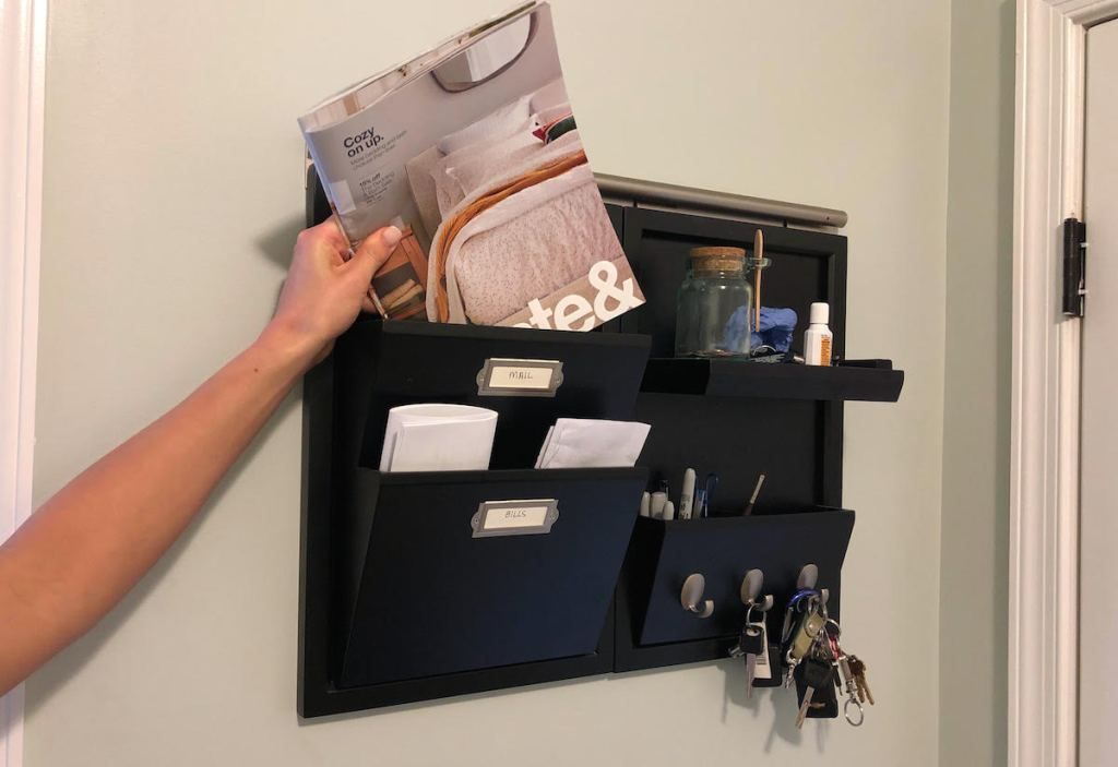 hand putting magazine in organizer bin on wall