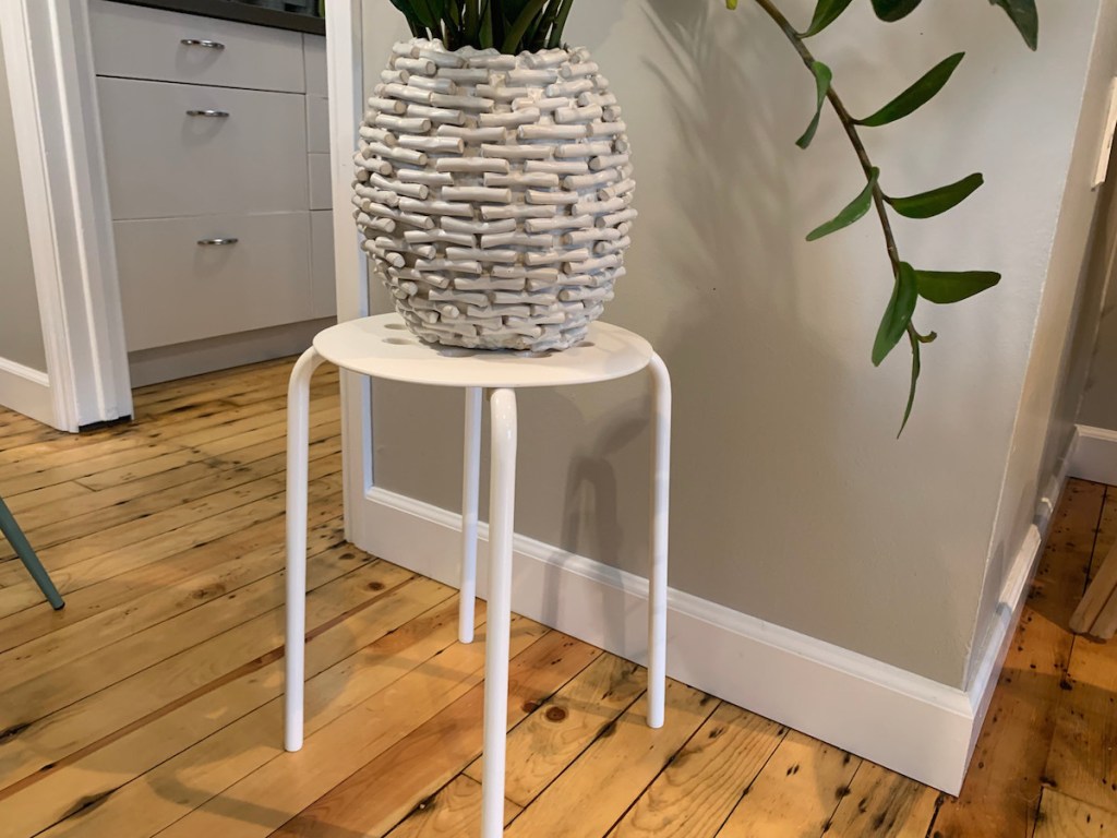 white ikea stool with white vase and plant on top