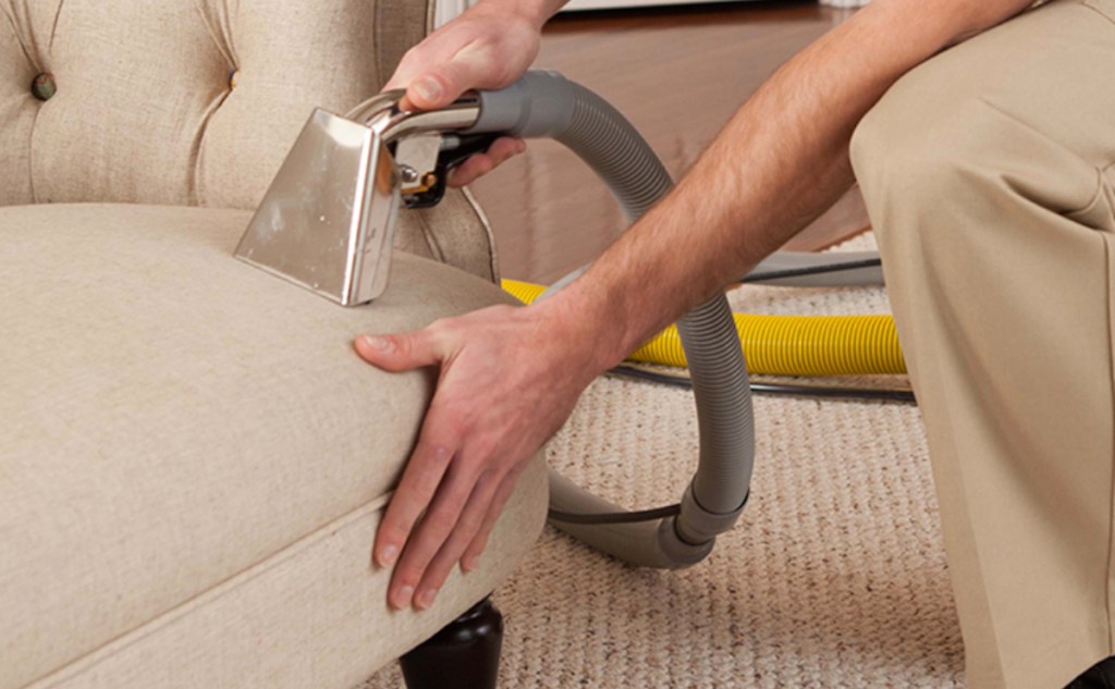 person steam cleaning beige tan couch sofa