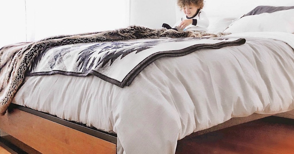 platform bed made with little boy sitting on it