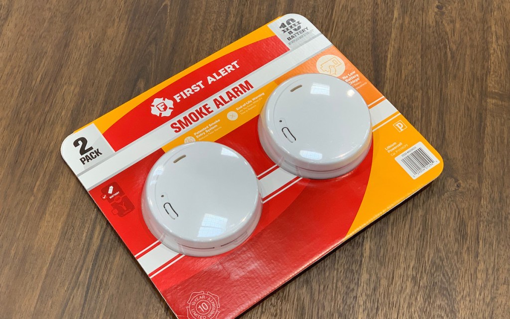 two smoke detectors sitting on counter in red packaging