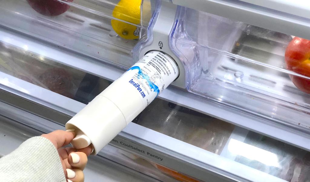 hand pulling out water filter from inside of refrigerator